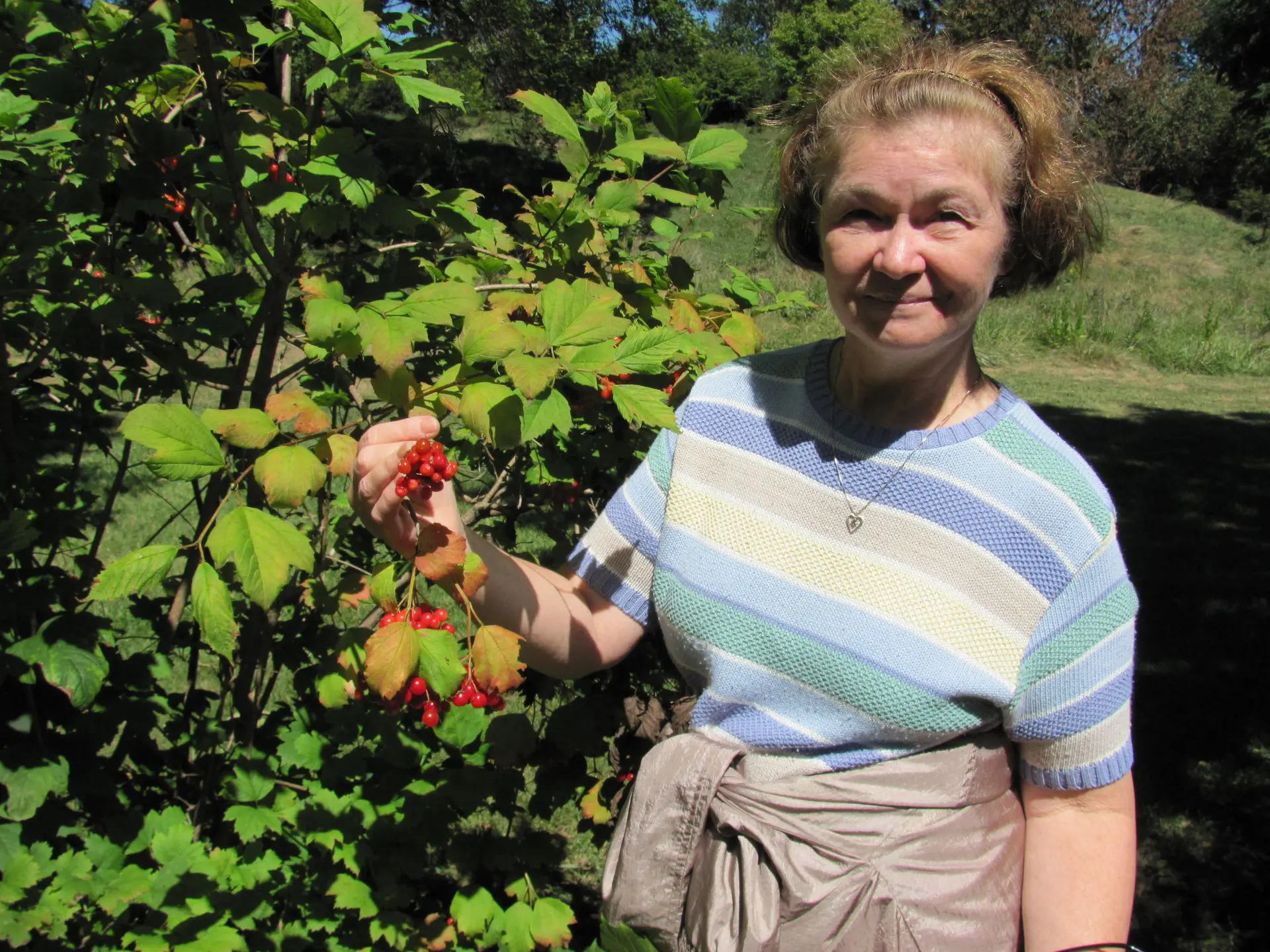 67ee9f854cc8f_plant health care A woman holding a bunch of fruit in her hand.