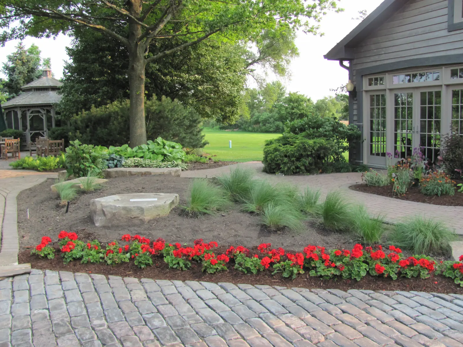 A brick walkway with red flowers in the middle of it.